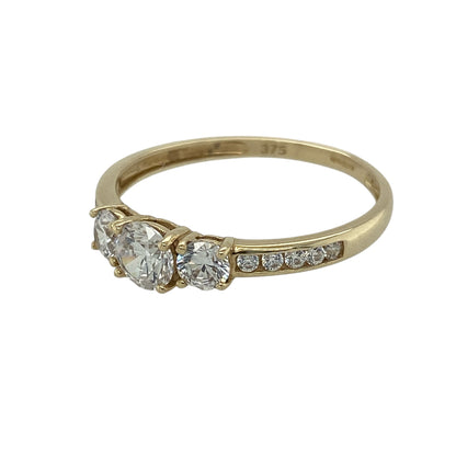 Bring classic sparkle and elegant detail to your jewellery collection with this pre-owned 9ct yellow gold cubic zirconia trilogy ring — a timeless piece with added brilliance.

Design: The ring features a 5mm round centre stone flanked by two 4mm stones, with additional smaller cubic zirconia set into the band for extra shimmer and sophistication.
Material: Made from 9ct yellow gold, the polished finish enhances the warm tone of the band and beautifully complements the bright sparkle of the stones.