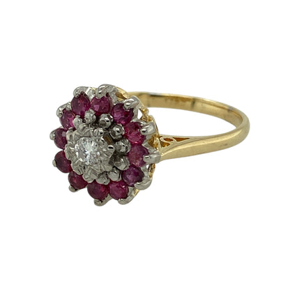 Bring luxurious colour contrast and classic brilliance to your jewellery collection with this pre-owned 18ct yellow and white gold diamond and ruby set cluster ring, a striking design with elegant presence and timeless appeal.

Design: The ring features a central diamond of approximately 0.11ct, surrounded by thirteen vivid rubies arranged in a classic cluster formation. The cluster front measures approximately 13mm in height, creating a bold and eye-catching focal point.