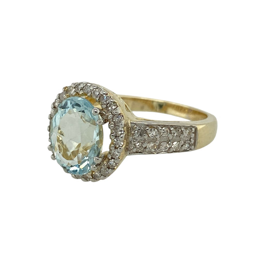Bring serene colour and elegant sparkle to your jewellery collection with this pre-owned 9ct yellow gold diamond and aquamarine set halo ring, a striking design with refined presence and timeless appeal.

Design: The ring features a central oval aquamarine gemstone measuring approximately 10mm by 8mm, framed by a halo of sparkling diamonds that enhance its soft blue tones and create a radiant focal point.