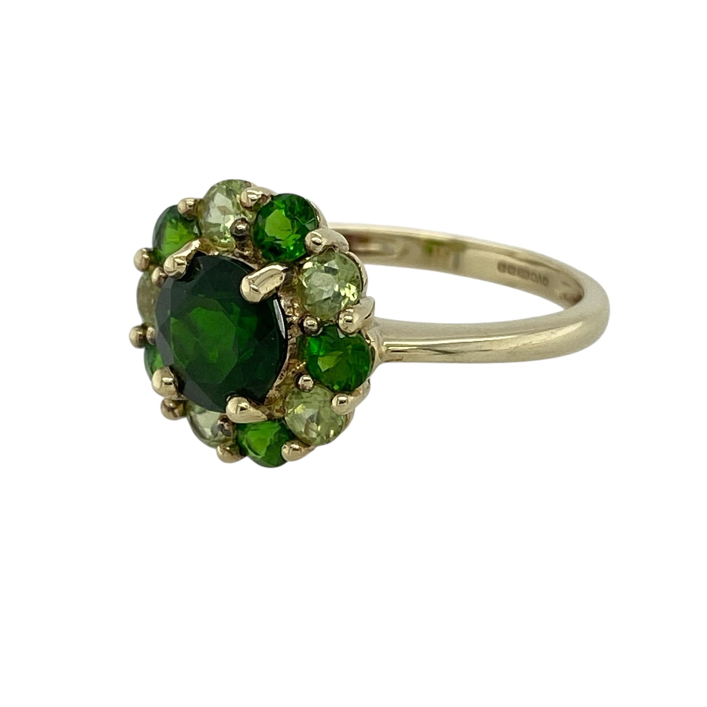 Bring vibrant colour and distinctive style to your jewellery collection with this pre-owned 9ct yellow gold three-tone green stone cluster ring, a striking design that celebrates natural green hues in an elegant cluster setting.

Design: The ring features a bold central green stone measuring approximately 7mm in diameter, surrounded by a cluster of complementary green gemstones in emerald, peridot, and chrome diopside tones. The varied shades create depth, contrast, and a visually captivating arrangement.