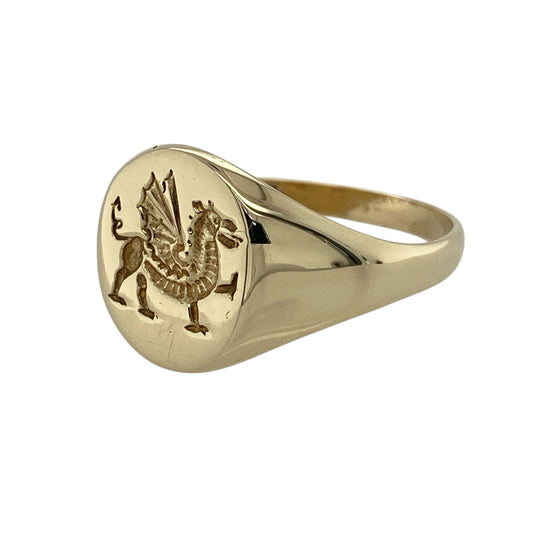Bring bold character and traditional symbolism to your jewellery collection with this pre-owned 9ct yellow gold Welsh dragon oval signet ring, a striking piece that celebrates heritage with timeless style.

Design: The ring features an oval signet face engraved with the iconic Welsh dragon, with the front measuring 14mm high for a strong and confident presence.
Material: Made from polished 9-carat yellow gold, the warm tone enhances the detailed dragon motif and classic signet form.