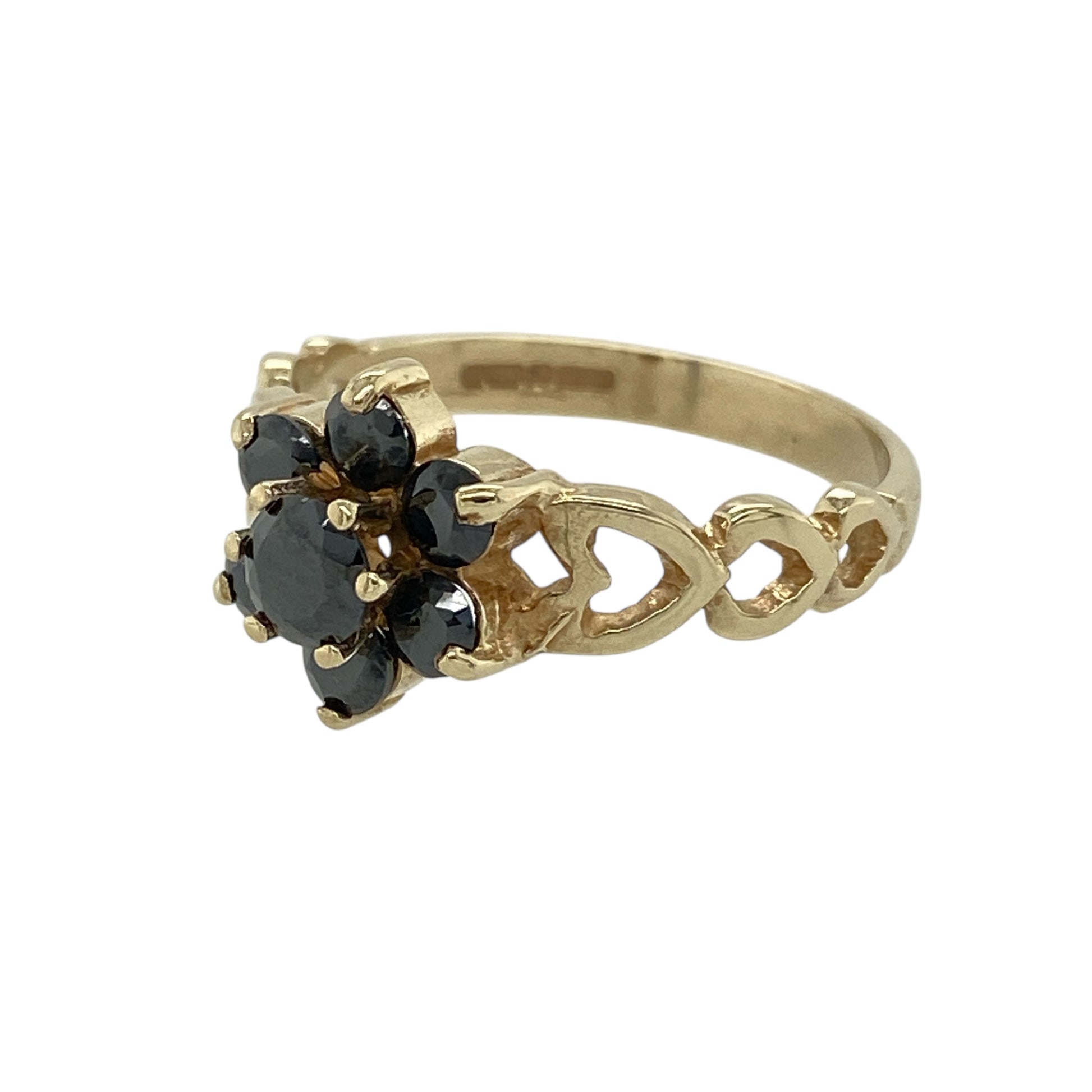Bring classic colour and romantic detailing to your jewellery collection with this pre-owned 9ct yellow gold sapphire set flower cluster ring, a beautifully styled piece with timeless appeal.

Design: The ring features a floral-inspired cluster with a central sapphire measuring approximately 4mm in diameter, forming an elegant focal point. The decorative front measures 10mm high, giving the ring a refined yet noticeable presence.