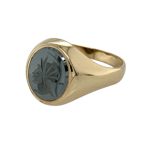 Bring bold character and classical influence to your jewellery collection with this pre-owned 9ct yellow gold hematite Centurion set oval signet ring, a striking piece inspired by historic Roman imagery.

Design: The ring features an oval hematite stone measuring 12mm by 10mm, engraved with a Centurion motif that creates a strong and distinctive focal point.
Material: Made from polished 9-carat yellow gold, the warm tone contrasts beautifully with the dark, glossy surface of the hematite.