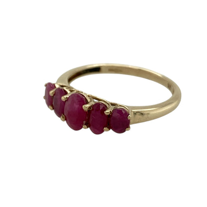 Bring rich colour and classic elegance to your jewellery collection with this pre-owned 9ct yellow gold ruby set five stone band ring, a timeless design with striking gemstone detail.

Design: The ring features a five-stone arrangement, highlighted by a central oval ruby measuring 6mm by 4mm, flanked by additional rubies that create a balanced and eye-catching display across the band.
Material: Made from polished 9-carat yellow gold, the warm tone beautifully enhances the deep red hues of the rubies.