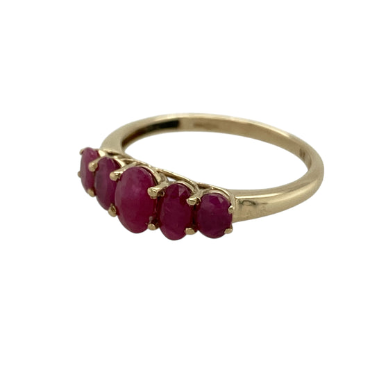 Bring rich colour and classic elegance to your jewellery collection with this pre-owned 9ct yellow gold ruby set five stone band ring, a timeless design with striking gemstone detail.

Design: The ring features a five-stone arrangement, highlighted by a central oval ruby measuring 6mm by 4mm, flanked by additional rubies that create a balanced and eye-catching display across the band.
Material: Made from polished 9-carat yellow gold, the warm tone beautifully enhances the deep red hues of the rubies.