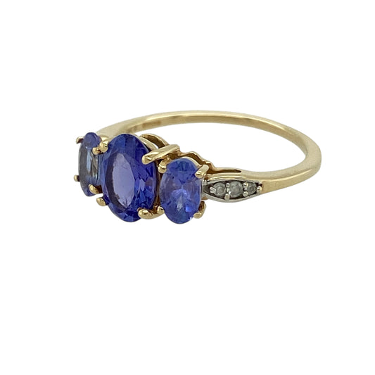 Bring soft colour and timeless symbolism to your jewellery collection with this pre-owned 9ct yellow gold tanzanite & cubic zirconia set trilogy ring, a graceful design with elegant sparkle.

Design: The ring features a classic trilogy arrangement with an oval tanzanite centre stone measuring 7mm by 5mm, flanked by two slightly smaller tanzanite stones, all complemented by cubic zirconia accents for added brilliance.