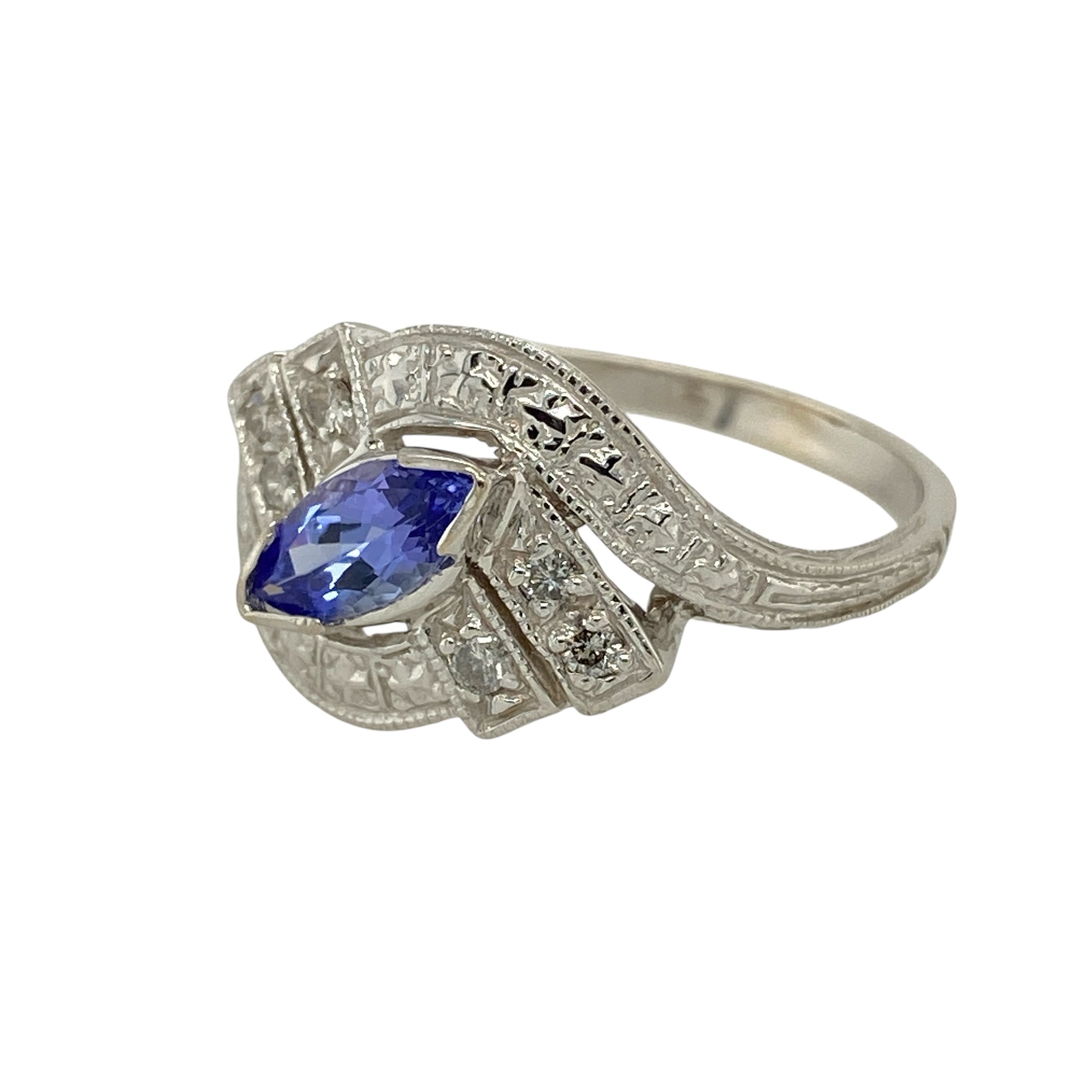 Bring elegant colour and refined sparkle to your jewellery collection with this pre-owned 14ct white gold diamond & tanzanite set ring, a beautifully detailed design with timeless sophistication.

Design: The ring features a marquise-cut tanzanite measuring 8mm by 4mm, creating a graceful centrepiece, surrounded by diamonds that enhance its shape and brilliance. The shoulders are finished with decorative patterned detailing, adding character and vintage-inspired charm.