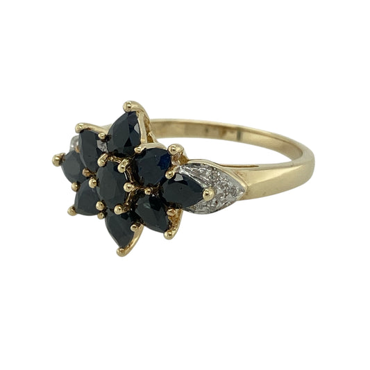 Bring classic colour and refined sparkle to your jewellery collection with this pre-owned 9ct yellow gold diamond & sapphire set cluster ring, a striking design with elegant presence.

Design: The ring features a traditional cluster arrangement of deep blue sapphires accented with diamonds, forming a bold and eye-catching focal point. The front of the ring measures 14mm high, giving it a strong yet balanced appearance on the finger.