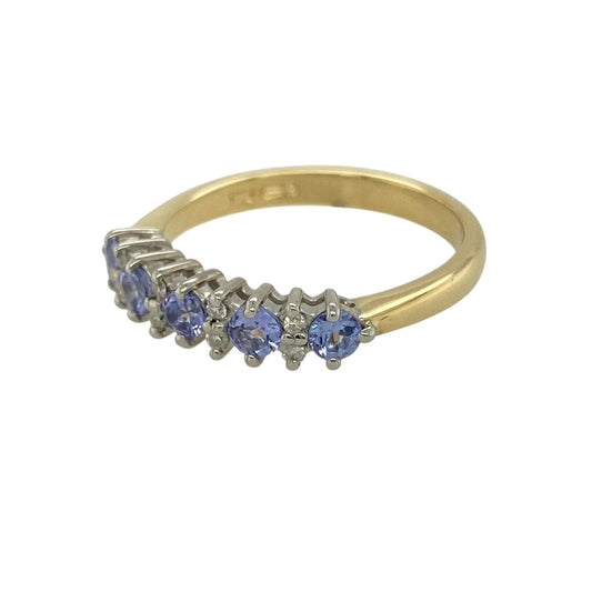 Bring luxurious colour and refined sparkle to your jewellery collection with this pre-owned 18ct yellow gold diamond and tanzanite set band ring, an elegant piece designed to make a timeless statement.

Design: This ring features a classic band style adorned with vivid round tanzanite stones, complemented by diamond accents that add balance and subtle brilliance across the front.