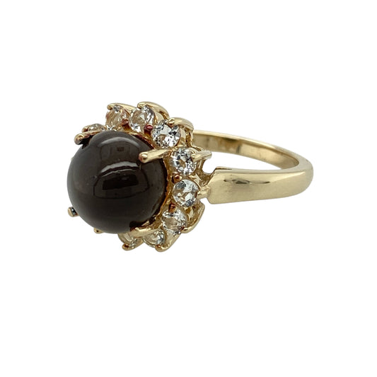 Bring distinctive light play and elegant sparkle to your jewellery collection with this pre-owned 9ct yellow gold cat’s eye and white topaz set cluster ring, a striking design with timeless appeal.

Design: This ring features a captivating round cat’s eye stone at the centre, surrounded by white topaz stones arranged in a classic cluster style that enhances brilliance and visual depth.