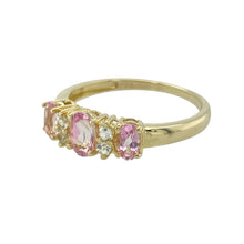 Load image into Gallery viewer, Add a pop of colour and sparkle to your jewellery collection with this pre-owned 9ct yellow gold band ring, featuring:

Design: A classic band style with a vibrant centre stone and white cubic zirconia accents for added brilliance.
Material: 9-carat yellow gold, offering a warm and polished finish.
Gemstone Detail: Features a 6mm by 4mm pink cubic zirconia at the centre, flanked by white stones for contrast and shimmer.
Size &amp; Fit: Designed in size P, ensuring a comfortable and flattering fit.

