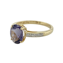 Load image into Gallery viewer, Introduce a touch of subtle luxury to your collection with this pre-owned 9ct yellow gold diamond and iolite set ring, featuring:

Design: A refined setting with a richly coloured centre stone and a diamond-set band for added sparkle and sophistication.
Material: 9-carat yellow gold, offering a classic and polished finish that enhances the gemstone&#39;s hue.
Gemstone Detail: Set with a 9mm by 7mm oval-cut iolite in a deep violet-blue tone, complemented by diamonds along the band for a graceful shimmer.

