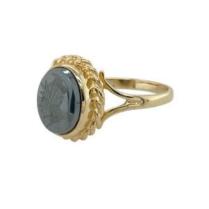 Bring bold character and classical detail to your collection with this pre-owned 9ct yellow gold hematite centurion set ring, featuring strong design and vintage appeal—perfect for statement styling or collectors of unique pieces.

Design: The ring showcases a 10mm by 8mm oval hematite stone engraved with a centurion figure, framed by a decorative rope-edge border for a traditional and striking finish.