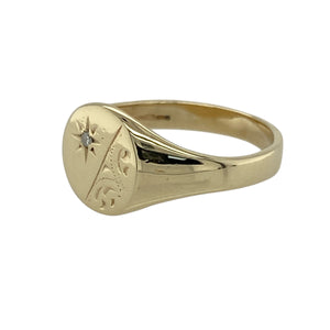 Bring timeless charm and refined sparkle to your jewellery collection with this pre-owned 9ct yellow gold patterned round diamond signet ring—perfect for adding elegance to a classic design.

Design: The ring features a 9mm high round face with fine patterned detailing and a central diamond for a subtle yet eye-catching finish.
Material: Made from 9-carat yellow gold, the polished surface enhances the warm golden tone and highlights the intricate design work.
