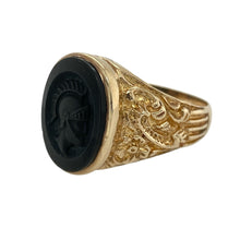 Load image into Gallery viewer, Bring bold design and historical character to your jewellery collection with this pre-owned 9ct yellow gold onyx centurion signet ring—perfect for making a confident and distinguished statement.

Design: The ring features a 16mm by 12mm oval onyx stone, inlaid with a detailed centurion motif, and finished with patterned shoulders for added texture and interest.
Material: Made from 9-carat yellow gold, the polished finish enhances the warm golden tone and provides a striking contrast to the deep black onyx.

