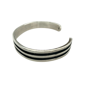 Bring bold contrast and modern edge to your collection with this pre-owned 925 silver black line detail cuff bangle, offering a sleek and structured design—perfect for everyday sophistication or statement styling.

Design: The bangle features a wide cuff profile with recessed black line detailing, adding depth and a contemporary finish to its clean, minimal silhouette.
Material: Made from 925 sterling silver, the polished surface contrasts beautifully