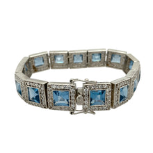Load image into Gallery viewer, Bring glamorous colour and sparkle to your collection with this pre-owned 925 silver blue stone and cubic zirconia set bracelet, offering a bold, eye-catching design perfect for special occasions or elevated everyday wear.

Design: The bracelet features a series of 13mm square links, each showcasing a 7mm by 7mm vivid blue stone framed by a halo of sparkling cubic zirconia, creating a striking contrast and luxurious look.


