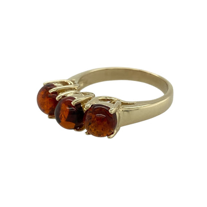 Bring warm, natural tones and classic symbolism to your jewellery collection with this pre-owned 9ct yellow gold amber set trilogy ring, a beautifully balanced design with timeless appeal.

Design: The ring features three oval amber stones, each measuring approximately 6mm in diameter, arranged in a traditional trilogy style to create a rich and eye-catching focal point.
Material: Made from polished 9-carat yellow gold, the warm golden tone perfectly complements the honeyed hues of the amber.