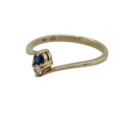 Add delicate colour and elegant sparkle to your jewellery collection with this pre-owned 9ct yellow gold diamond and sapphire twist ring, offering a refined design with subtle contrast.

Design: This ring features a graceful twist-style band showcasing a round sapphire measuring approximately 2mm in diameter, positioned above a brilliant cut diamond for a layered and eye-catching look.