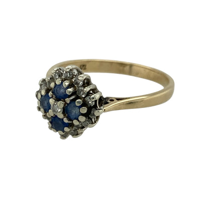 Add rich colour and classic sparkle to your jewellery collection with this pre-owned 9ct yellow gold diamond and sapphire cluster ring, offering timeless elegance in a refined design.

Design: This ring features a cluster-style front measuring approximately 11mm in height, made up of four sapphire stones surrounded by diamonds, creating a balanced and eye-catching focal point.