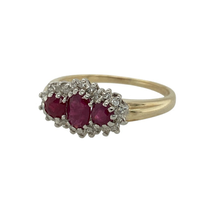 Add vibrant colour and timeless sparkle to your jewellery collection with this pre-owned 9ct yellow gold diamond and ruby set cluster trilogy ring, combining classic styling with elegant detail. A striking piece perfect for special occasions or refined everyday wear.

Design: The ring features a 5mm by 4mm oval-cut ruby at its centre, framed within a cluster setting to enhance its presence and rich red hue.