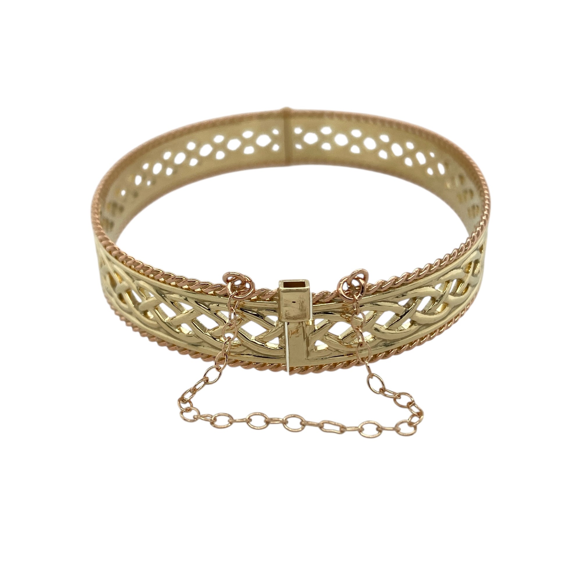 Celebrate heritage and craftsmanship with this pre-owned 9ct yellow and rose gold Clogau open Celtic weave bangle—a striking statement piece rich in traditional Welsh design.

Design: The bangle features an intricate open Celtic weave pattern across the centre, framed by a detailed rope edge that adds texture and definition. The 10mm width gives the piece a bold and eye-catching presence, while the 6cm diameter offers a comfortable and flattering fit on the wrist.