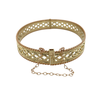 Celebrate heritage and craftsmanship with this pre-owned 9ct yellow and rose gold Clogau open Celtic weave bangle—a striking statement piece rich in traditional Welsh design.

Design: The bangle features an intricate open Celtic weave pattern across the centre, framed by a detailed rope edge that adds texture and definition. The 10mm width gives the piece a bold and eye-catching presence, while the 6cm diameter offers a comfortable and flattering fit on the wrist.