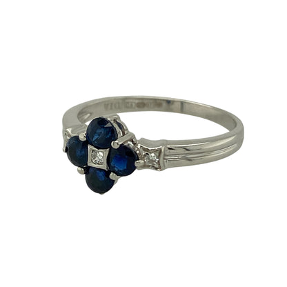 Add timeless elegance and rich colour to your jewellery collection with this pre-owned 9ct white gold diamond and sapphire flower cluster ring—an eye-catching design perfect for special occasions or refined everyday wear.

Design: The front of the ring measures approximately 8mm high and features a delicate flower cluster formation set with sapphire stones, each approximately 3mm in diameter. Sparkling diamond accents enhance the floral arrangement, creating a beautifully balanced and radiant finish.