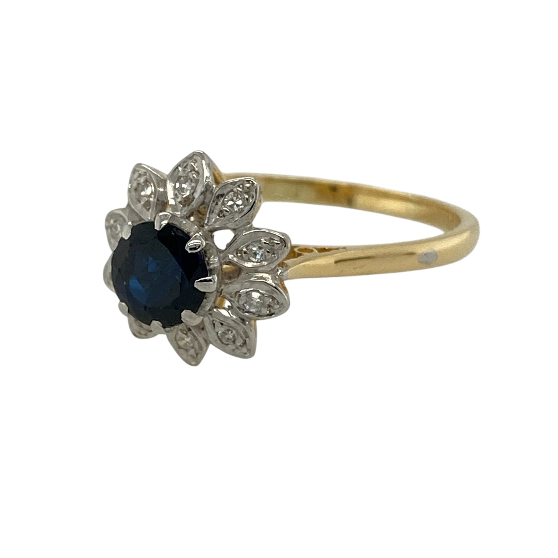 Add timeless colour and elegant sparkle to your jewellery collection with this pre-owned 18ct yellow and white gold diamond and sapphire flower cluster ring, featuring a classic floral-inspired design—perfect for special occasions or everyday luxury.

Design: The ring showcases a beautiful flower cluster design with a round sapphire at the centre measuring approximately 6mm in diameter, surrounded by sparkling diamonds that form delicate petal-like accents.