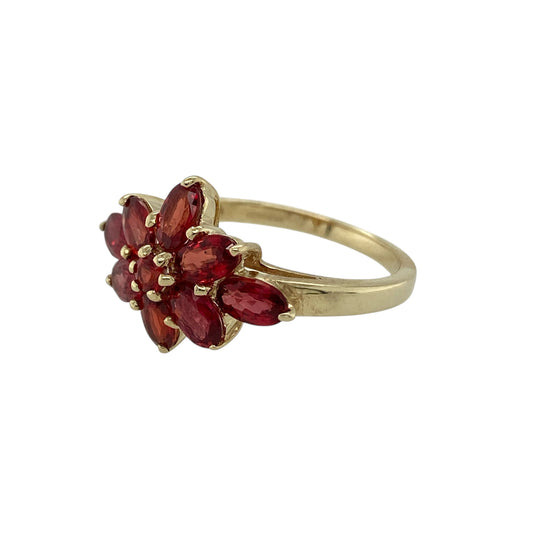Add vibrant colour and classic elegance to your jewellery collection with this pre-owned 9ct yellow gold red stone flower cluster ring, featuring a timeless floral design—perfect for everyday wear or as a charming dress ring.

Design: The ring showcases a pretty flower cluster arrangement formed from rich red stones, creating a striking floral-inspired display across the finger. The cluster design gives the ring a balanced and eye-catching appearance with beautiful depth of colour.
