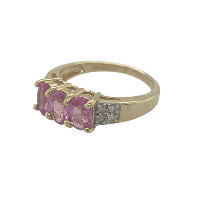 Add soft colour and timeless elegance to your jewellery collection with this pre-owned 9ct yellow gold diamond and pink sapphire trilogy ring, featuring a classic three-stone design with delicate sparkle—perfect for everyday wear or meaningful gifting.

Design: The ring showcases a trilogy arrangement with a central pink sapphire measuring approximately 6mm by 4mm, flanked by sparkling diamonds.