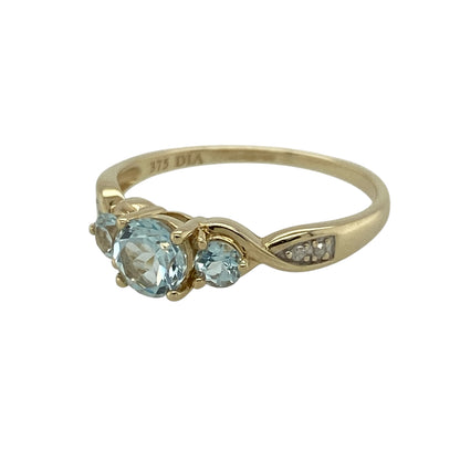 Add a fresh touch of colour and sparkle to your jewellery collection with this pre-owned 9ct yellow gold diamond and aqua coloured trilogy ring—an elegant piece perfect for everyday wear or special occasions.

Design: This trilogy ring features a central aqua coloured stone measuring approximately 5mm in diameter, flanked by two smaller matching stones of approximately 3mm each, creating a balanced and eye-catching look. Sparkling diamonds on the shoulders add extra brilliance and detail.