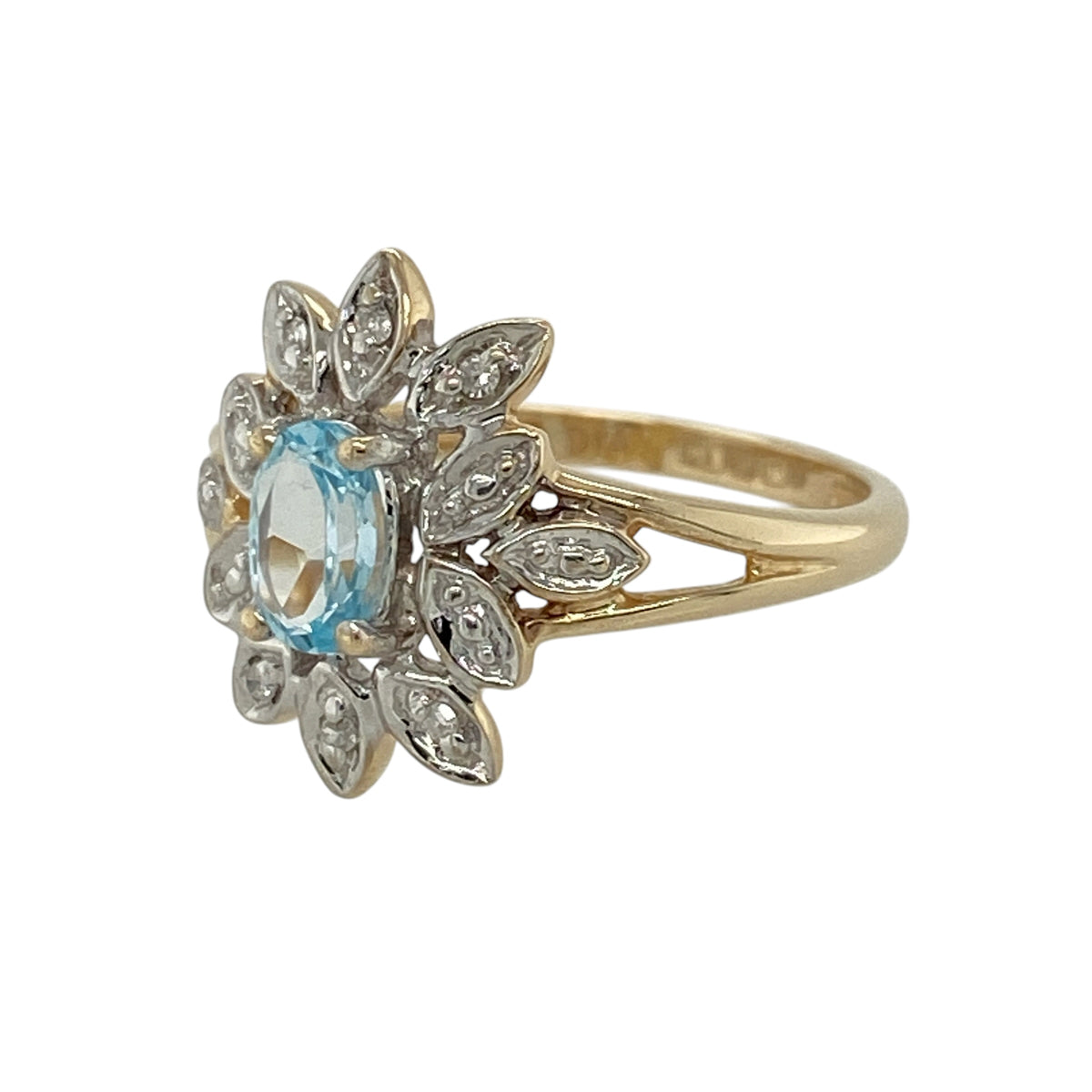Add a touch of vibrant colour and elegant sparkle to your jewellery collection with this pre-owned 9ct yellow and white gold diamond and blue topaz set flower cluster ring—an eye-catching piece perfect for everyday wear or special occasions.

Design: This ring features a striking flower cluster design with a 14mm high front, centred with an oval blue topaz measuring approximately 6mm by 4mm, surrounded by sparkling diamonds that form delicate petal shapes.