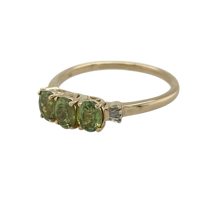 Add a fresh touch of colour and refined sparkle to your jewellery collection with this pre-owned 9ct yellow gold diamond and peridot set trilogy ring—an elegant piece perfect for everyday wear or special occasions.

Design: This ring features three oval peridot stones, each measuring approximately 5mm by 4mm, arranged in a classic trilogy formation. Small baguette-cut diamonds are set on each side, adding a sophisticated and structured sparkle.