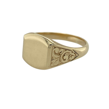 Add classic style with a decorative twist to your jewellery collection with this pre-owned 9ct yellow gold signet ring, featuring a clean polished face and detailed patterned shoulders—ideal for everyday wear or a timeless statement look.

Design: The ring features a plain signet face measuring approximately 10mm high, offering a smooth polished surface, complemented by patterned shoulders that add texture and character.