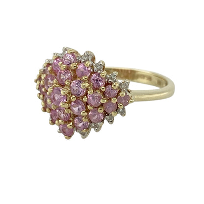 Add soft colour and eye-catching sparkle to your jewellery collection with this pre-owned 9ct yellow gold diamond and pink sapphire cluster ring, featuring a bold and feminine design—perfect for special occasions or standout everyday wear.

Design: The ring features a cluster of multiple round pink sapphires forming a vibrant centre, surrounded by small diamonds that add brilliance and create a striking halo effect.