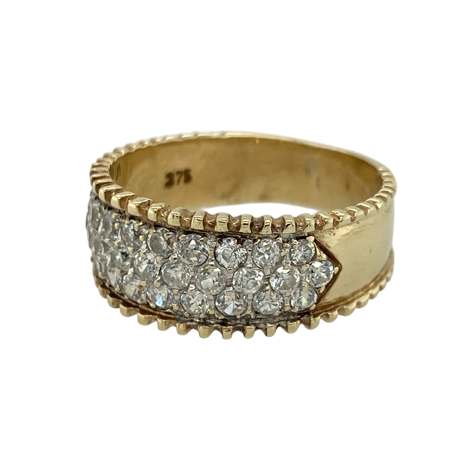 Add bold sparkle to your jewellery collection with this pre-owned 9ct yellow gold cubic zirconia set band ring, featuring a wide design with brilliant multi-row detailing—perfect for statement wear or special occasions.

Design: The ring features multiple round cubic zirconia stones arranged in three rows across the front, creating a dazzling and eye-catching display of sparkle.