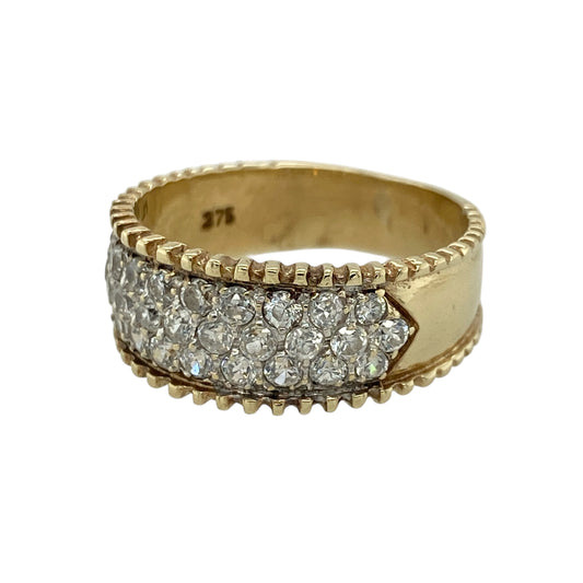 Add bold sparkle to your jewellery collection with this pre-owned 9ct yellow gold cubic zirconia set band ring, featuring a wide design with brilliant multi-row detailing—perfect for statement wear or special occasions.

Design: The ring features multiple round cubic zirconia stones arranged in three rows across the front, creating a dazzling and eye-catching display of sparkle.