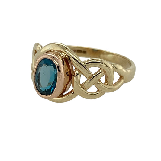 Bring colour, heritage, and elegance to your collection with this pre-owned 9ct yellow and rose gold blue topaz set Clogau ring—a beautifully designed piece inspired by Celtic tradition and timeless style.

Design: The ring features a 7mm by 5mm oval blue topaz at the centre, framed by intricately detailed Celtic-style shoulders that add depth and symbolism to the design.