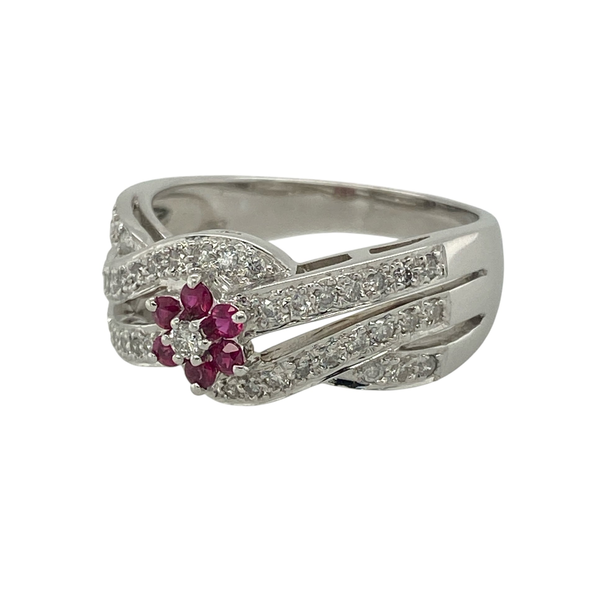 Add luxurious sparkle and rich colour to your collection with this pre-owned 14ct white gold diamond and ruby set flower cluster band ring—an eye-catching piece with elegant detail and timeless appeal.

Design: The ring features a 9mm wide front with a delicate flower cluster at the centre, formed by a small ruby surrounded by sparkling diamonds. The shoulders are designed with crossover open bands, set with additional diamonds for enhanced brilliance and a layered look.