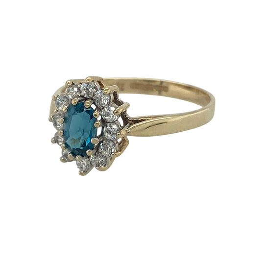Add a touch of colour and sparkle to your collection with this pre-owned 9ct yellow gold blue topaz and cubic zirconia set cluster ring—an elegant piece with timeless appeal.

Design: The ring features a 6mm by 4mm oval blue topaz at the centre, surrounded by a cluster of sparkling cubic zirconia that enhance its soft blue tone and create a bright focal point.