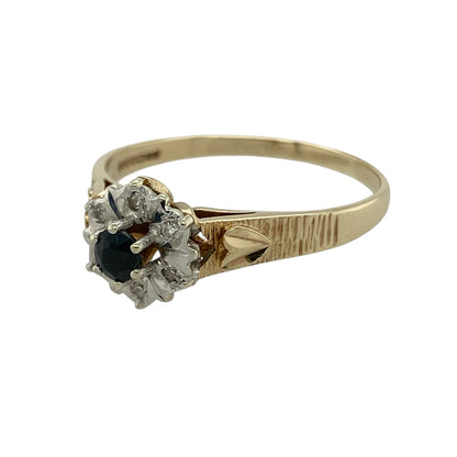 Add elegant colour and timeless sparkle to your collection with this pre-owned 9ct yellow and white gold diamond and sapphire set cluster ring—an eye-catching piece with classic appeal.

Design: The ring features a 4mm round sapphire at the centre, surrounded by a cluster of sparkling diamonds that enhance its deep blue tone and create a bright, refined focal point.