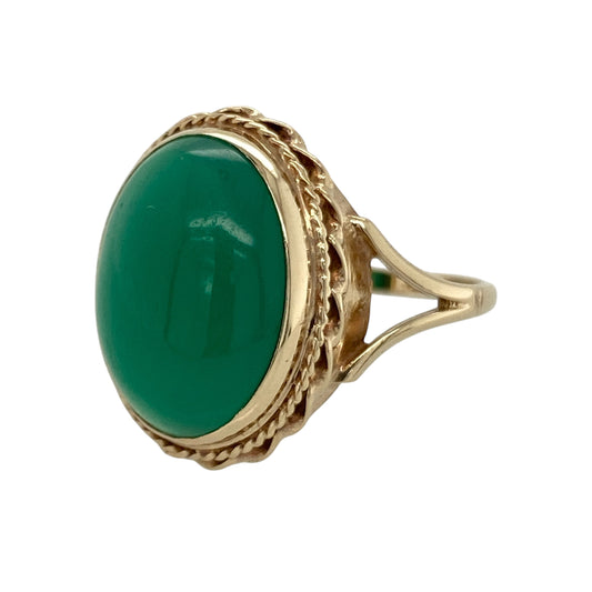 Bring bold colour and vintage-inspired elegance to your collection with this pre-owned 9ct yellow gold green stone ring, featuring an eye-catching oval centre and decorative detailing—perfect for making a statement on any occasion.

Design: The ring showcases a large oval green stone measuring approximately 15mm by 12mm, framed by a distinctive rope-style surround that adds texture and a classic decorative finish.