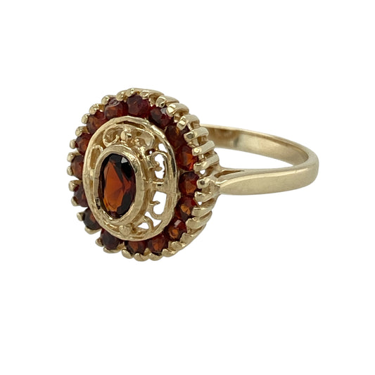 Bring rich colour and vintage-inspired charm to your collection with this pre-owned 9ct yellow gold garnet oval cluster ring, featuring a deep red centre stone and sparkling surrounding detail—perfect for both everyday elegance and special occasions.

Design: The ring showcases a 5mm by 3mm oval garnet at the centre, surrounded by smaller stones in a classic cluster formation, with the front of the ring measuring approximately 13mm in height for a bold yet refined look.