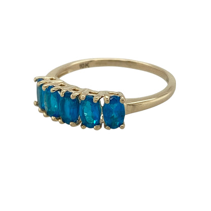 Bring vibrant colour and classic elegance to your collection with this pre-owned 9ct yellow gold blue stone set band ring, featuring a refined row of gemstones—perfect for everyday wear or special occasions.

Design: The ring features five oval blue stones, each measuring approximately 5mm by 3mm, arranged across the band to create a balanced and eye-catching look.