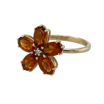 Bring vibrant colour and playful elegance to your collection with this pre-owned 9ct yellow gold diamond and orange stone flower ring, featuring a bold floral design with eye-catching detail—perfect for adding a pop of colour to any outfit.

Design: The ring showcases a flower-inspired cluster design measuring approximately 15mm in height, formed from orange stones each measuring around 6mm by 4mm, with a small diamond set at the centre for added sparkle.