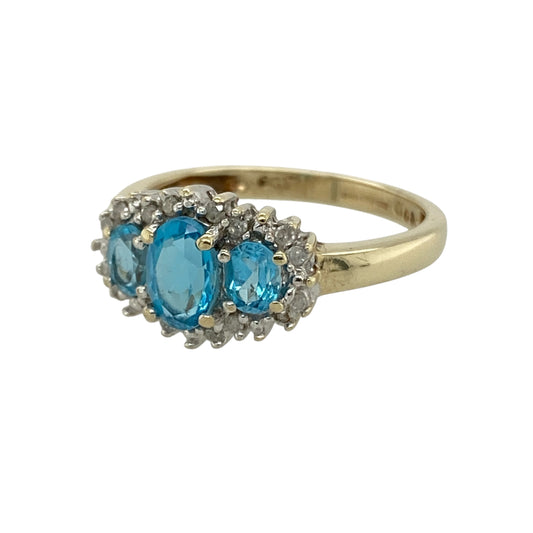 Bring vibrant colour and elegant sparkle to your collection with this pre-owned 9ct yellow gold diamond and blue topaz trilogy cluster ring, featuring a timeless design with refined detail—perfect for everyday wear or special occasions.

Design: The ring showcases a trilogy-style cluster arrangement centred around a 6mm by 4mm blue topaz, accented with sparkling diamonds that enhance the brilliance and create a balanced, eye-catching look.