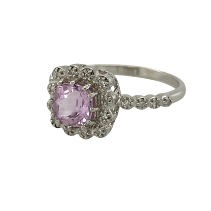 Bring feminine colour and elegant sparkle to your collection with this pre-owned 9ct white gold diamond and pink stone halo ring, featuring a sophisticated design with timeless appeal—perfect for special occasions or everyday glamour.

Design: The ring showcases a 6mm by 6mm cushion-cut pink stone at the centre, surrounded by a halo of sparkling diamonds with additional diamonds set along the shoulders for added brilliance and elegance.