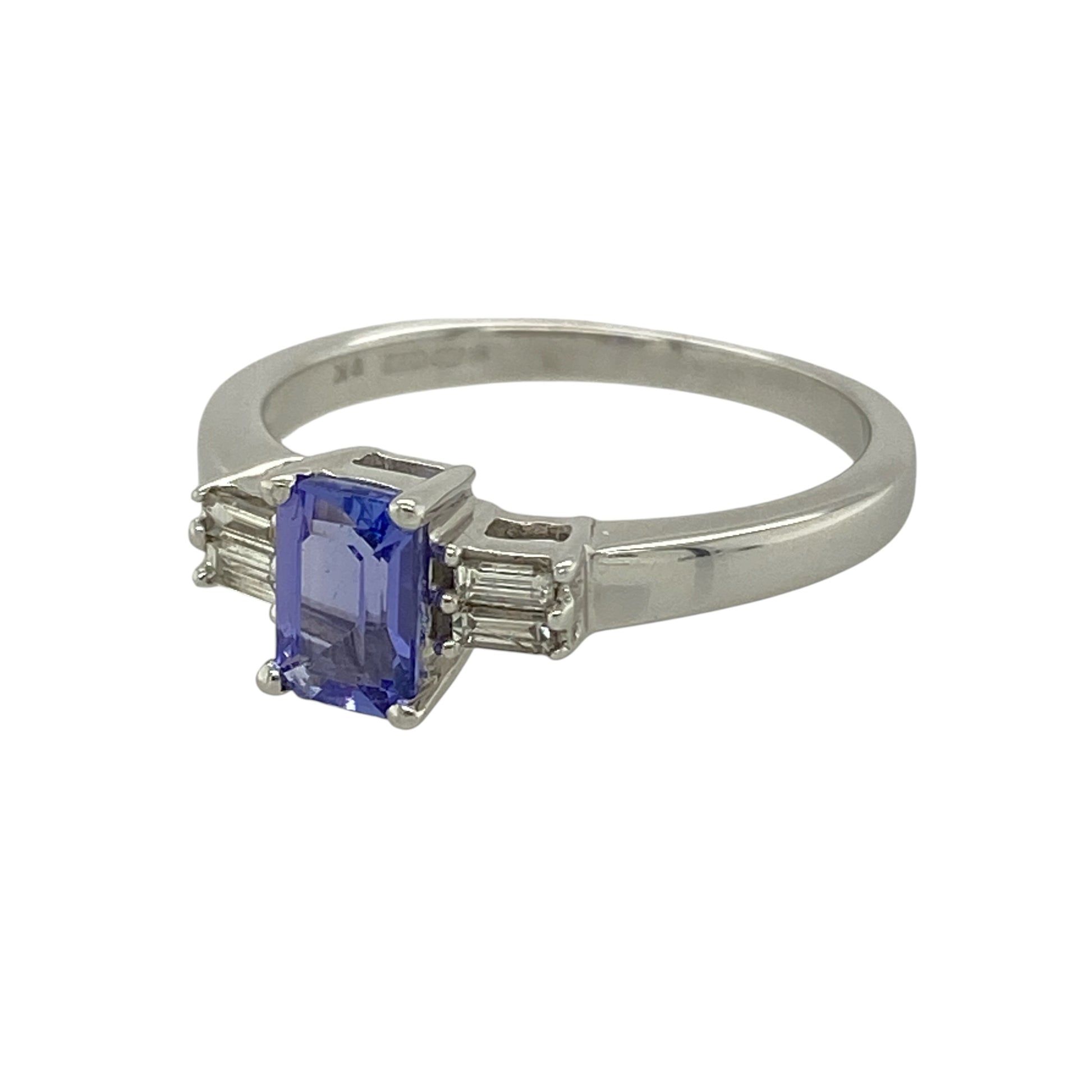 Bring elegant colour and refined sparkle to your collection with this pre-owned 9ct white gold diamond and tanzanite ring, featuring a sophisticated design with timeless appeal—perfect for special occasions or everyday luxury.

Design: The ring showcases a 6mm by 4mm rectangular tanzanite at the centre, accented by two baguette cut diamonds on either side for a balanced and elegant finish.