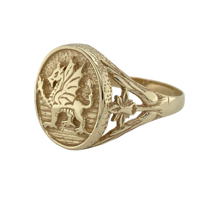 Celebrate Welsh heritage in timeless style with this pre-owned 9ct yellow gold Welsh Dragon oval signet ring, featuring a bold traditional design with detailed daffodil shoulders—perfect for statement wear, collectors, or meaningful everyday jewellery.

Design: The ring showcases a striking oval signet front featuring the iconic Welsh Dragon motif, measuring approximately 18mm high for a bold and eye-catching appearance.